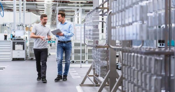Two man walking in a factory one holding a tablet