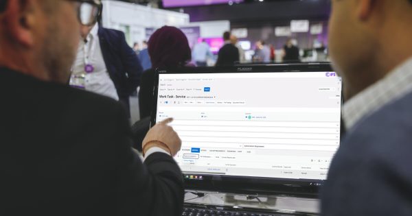 Two man in exhibition hall looking at a computer screen
