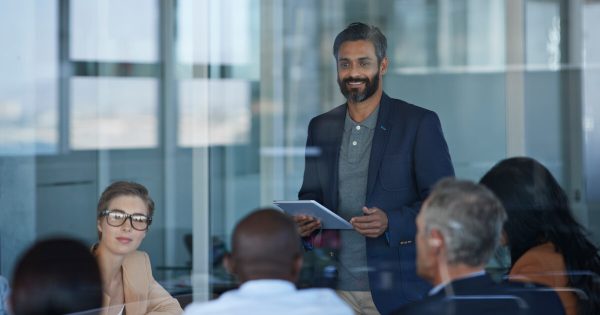 Man holding a tablet talking to a group of people