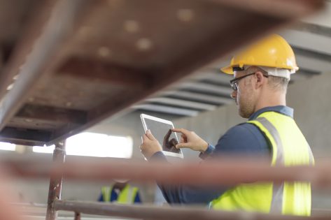 Architect in construction and engineering industry, using Industrial AI on laptop at construction site