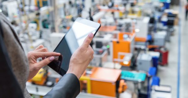 Mies käyttää ERP-ohjelmaa tabletilla tehtaalla