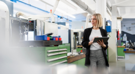 Woman using a tablet to assess service operations on a factory floor, illustrating the journey toward service-centric.