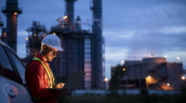 Field service technician wearing a hard hat and working on his laptop working with IFS Service Management specialists in SAP integrations.