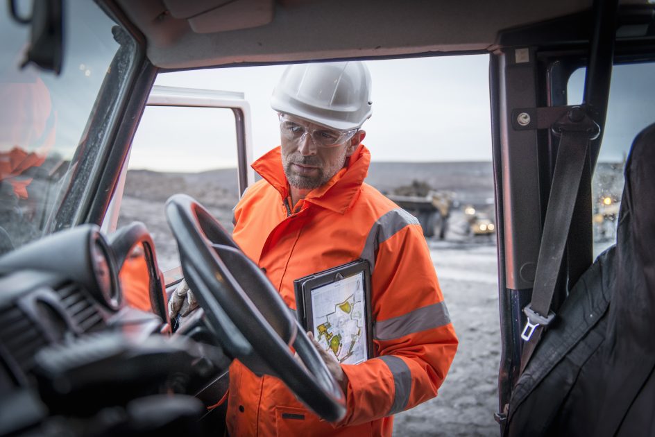 Geologist holding digital tablet on digital mining in truck in surface coal mine